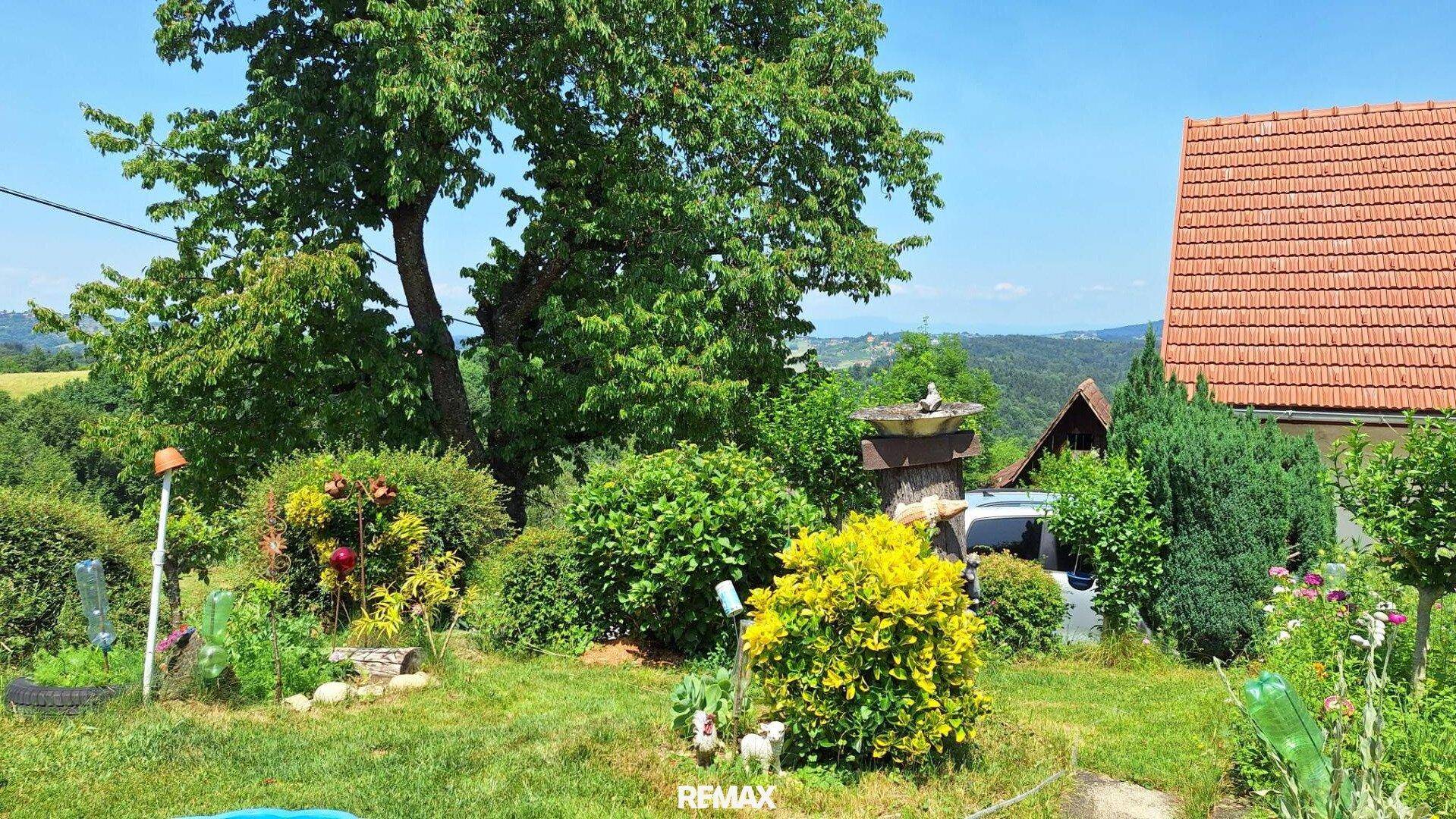 Gepflegter Garten mit verschiedenen Pflanzen, Sträuchern und weitem Blick in die Landschaft.