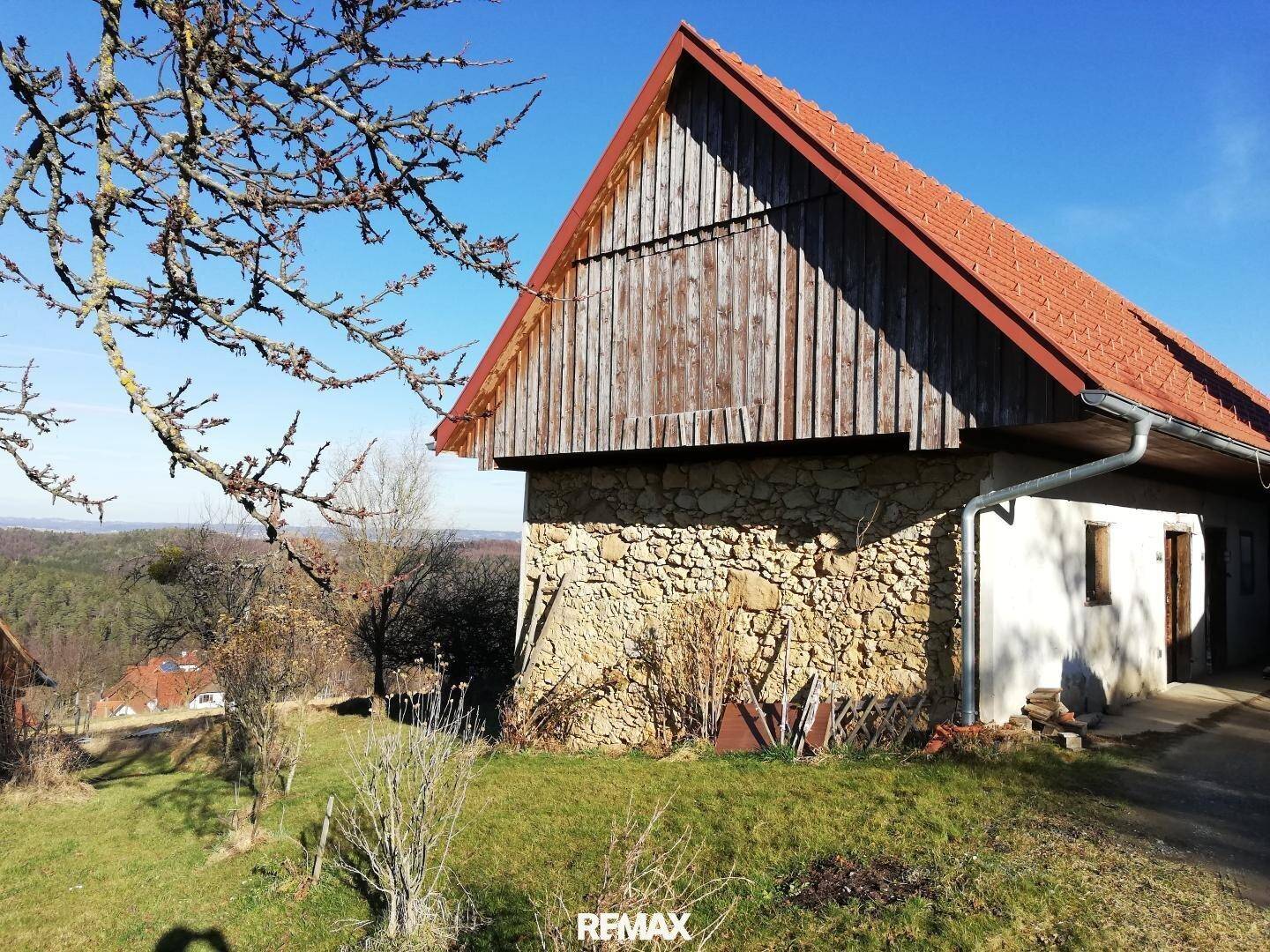 Rustikale Scheune mit Holzwänden und Steinfundament, eingebettet in die ländliche Umgebung.