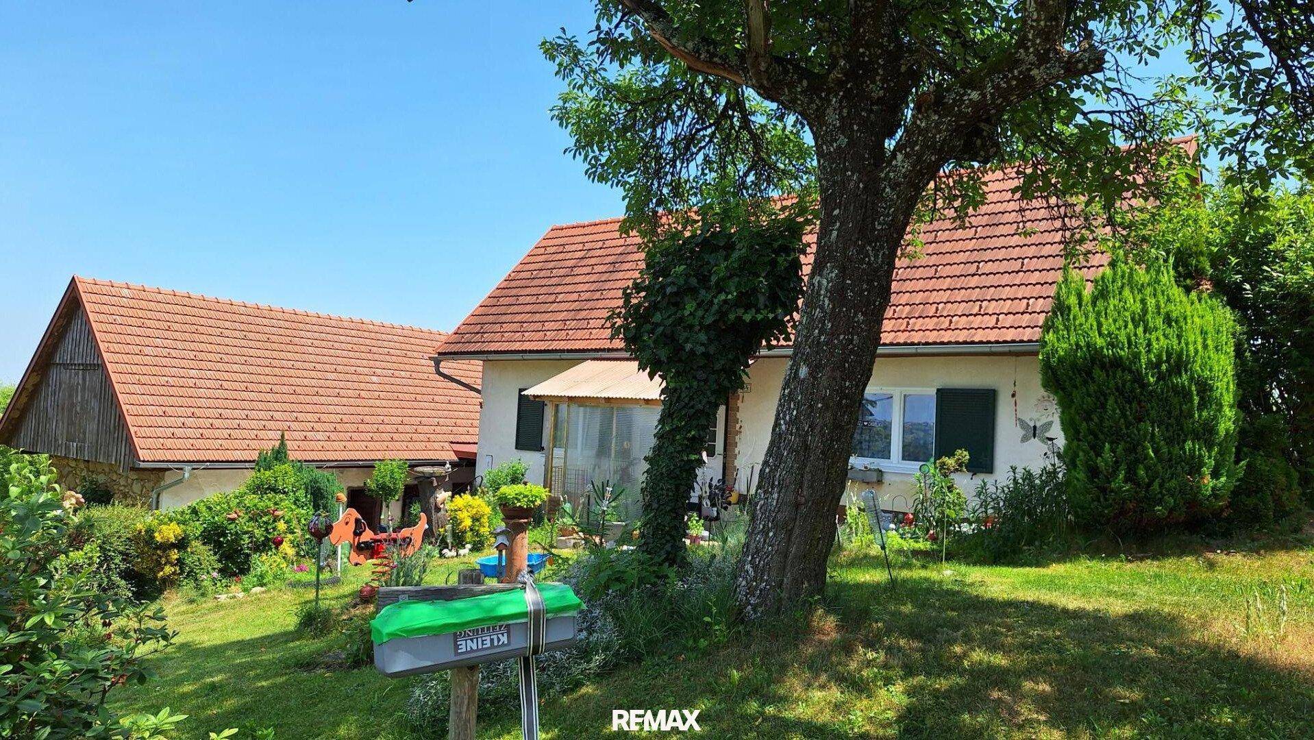 Charmantes Landhaus mit rotem Ziegeldach und einem gepflegten Garten mit altem Baumbestand.