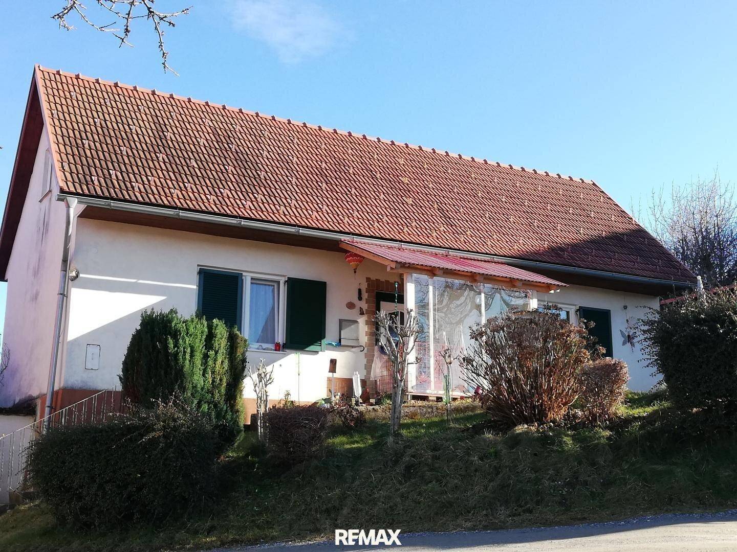 Ländliches Wohnhaus mit rotem Ziegeldach und einer kleinen überdachten Veranda im Eingangsbereich.