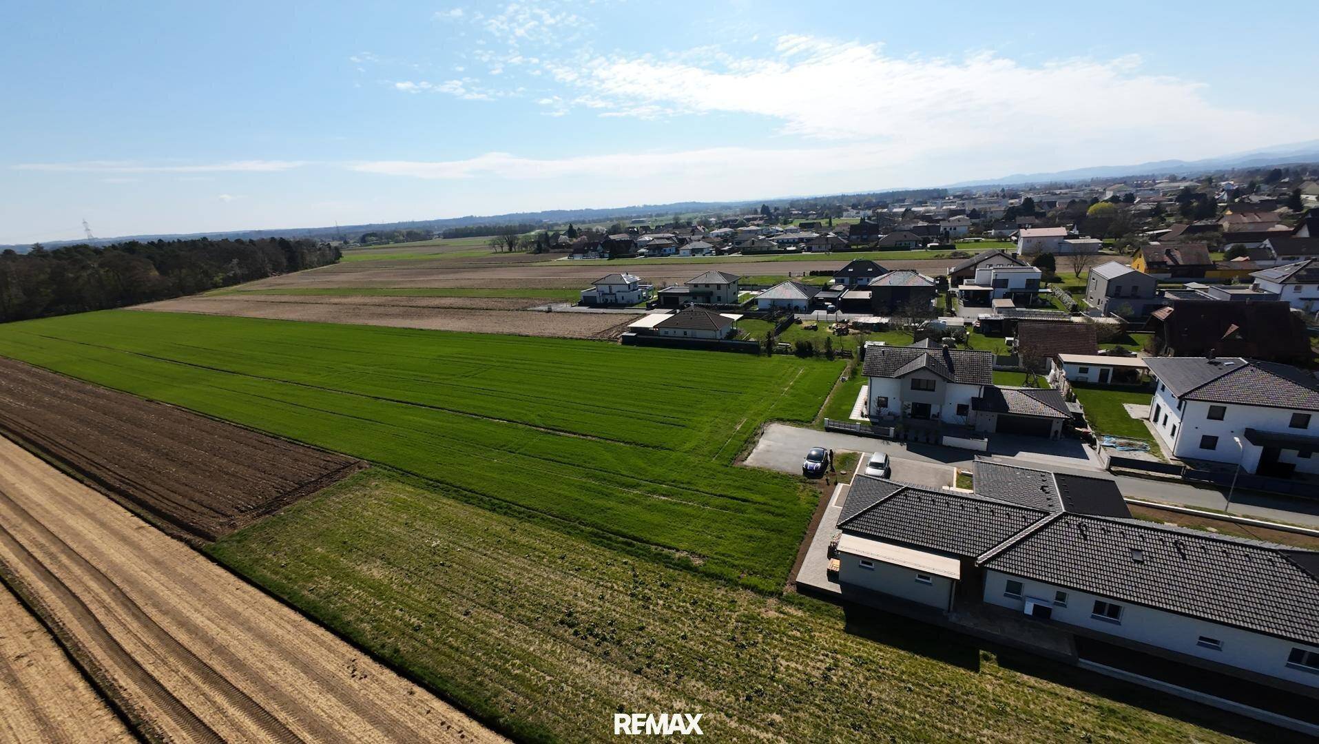 Panoramische Luftaufnahme einer ländlichen Wohngegend mit weiten Feldern und Siedlungshäusern.