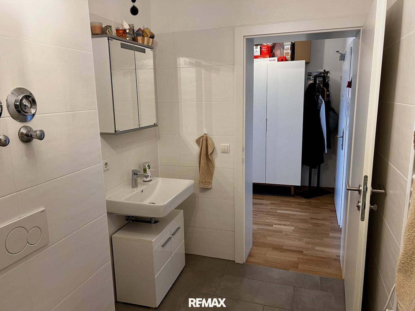 Funktionales Badezimmer mit Waschbecken, Spiegelschrank und Zugang zu einem angrenzenden Raum.
