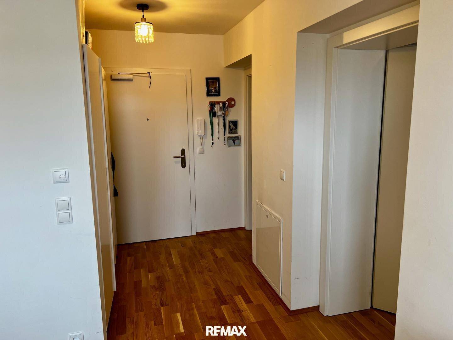 Heller Eingangsbereich mit Holzboden, Zugang zur Wohnung und einem Aufzug im Gebäude.