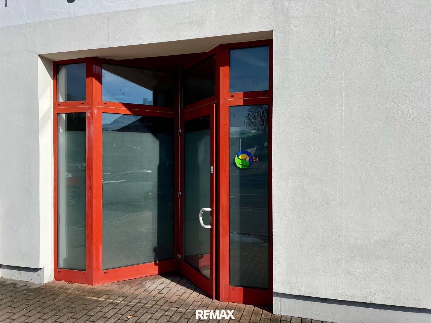 Detailansicht der roten Eingangstür mit großen Glasflächen, die viel Tageslicht in das Gebäude lassen.
