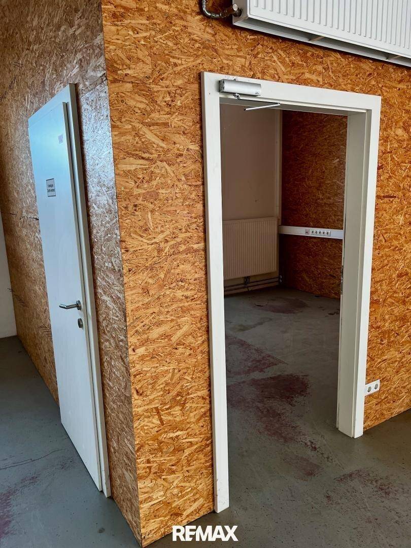 Innenansicht mit zwei Türen in einer Wand aus Holzspanplatten, die zu weiteren Räumen führen.