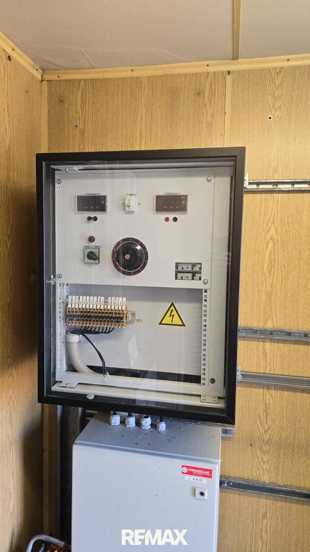 Elektrische Steuerungseinheit in einem Technikraum mit Holzverkleidung an den Wänden.