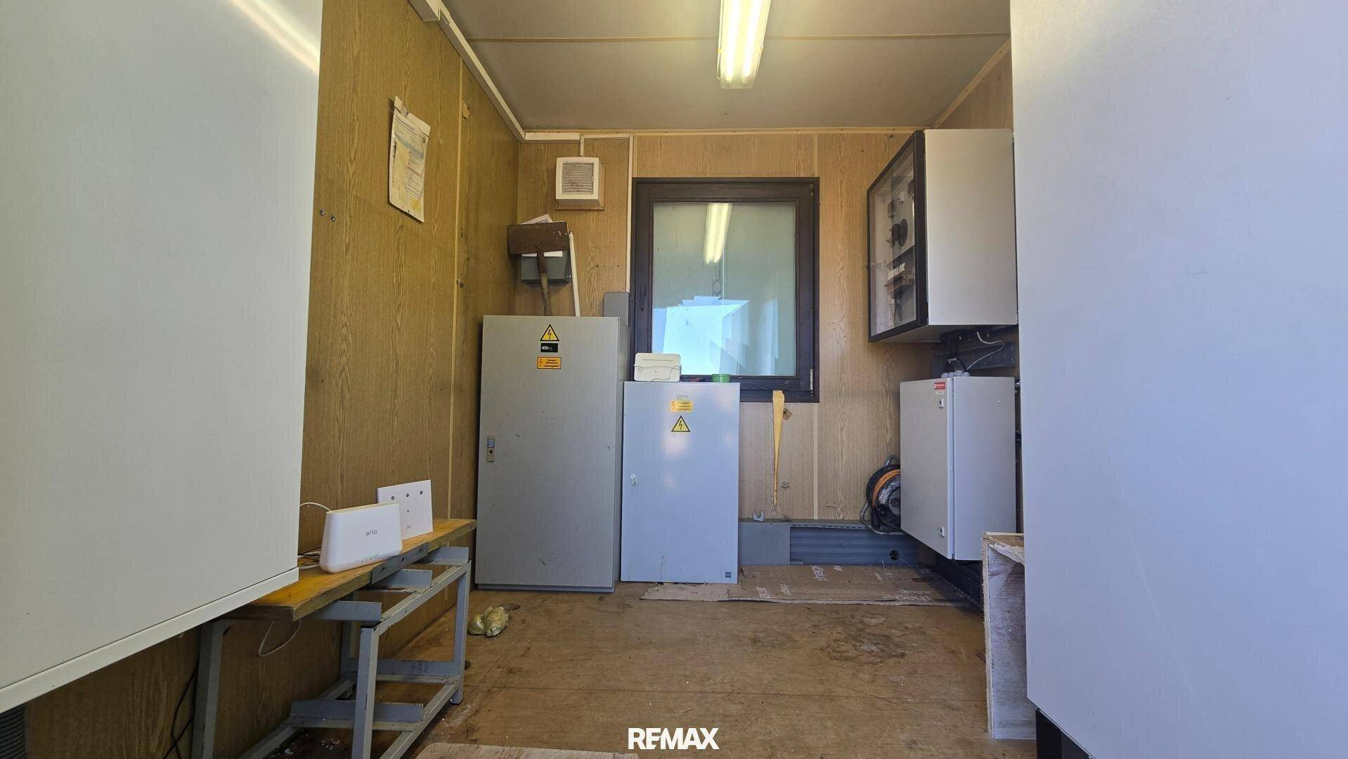 Kleiner Technikraum mit mehreren Elektroschränken, einem Fenster und einer einfachen Werkbank.
