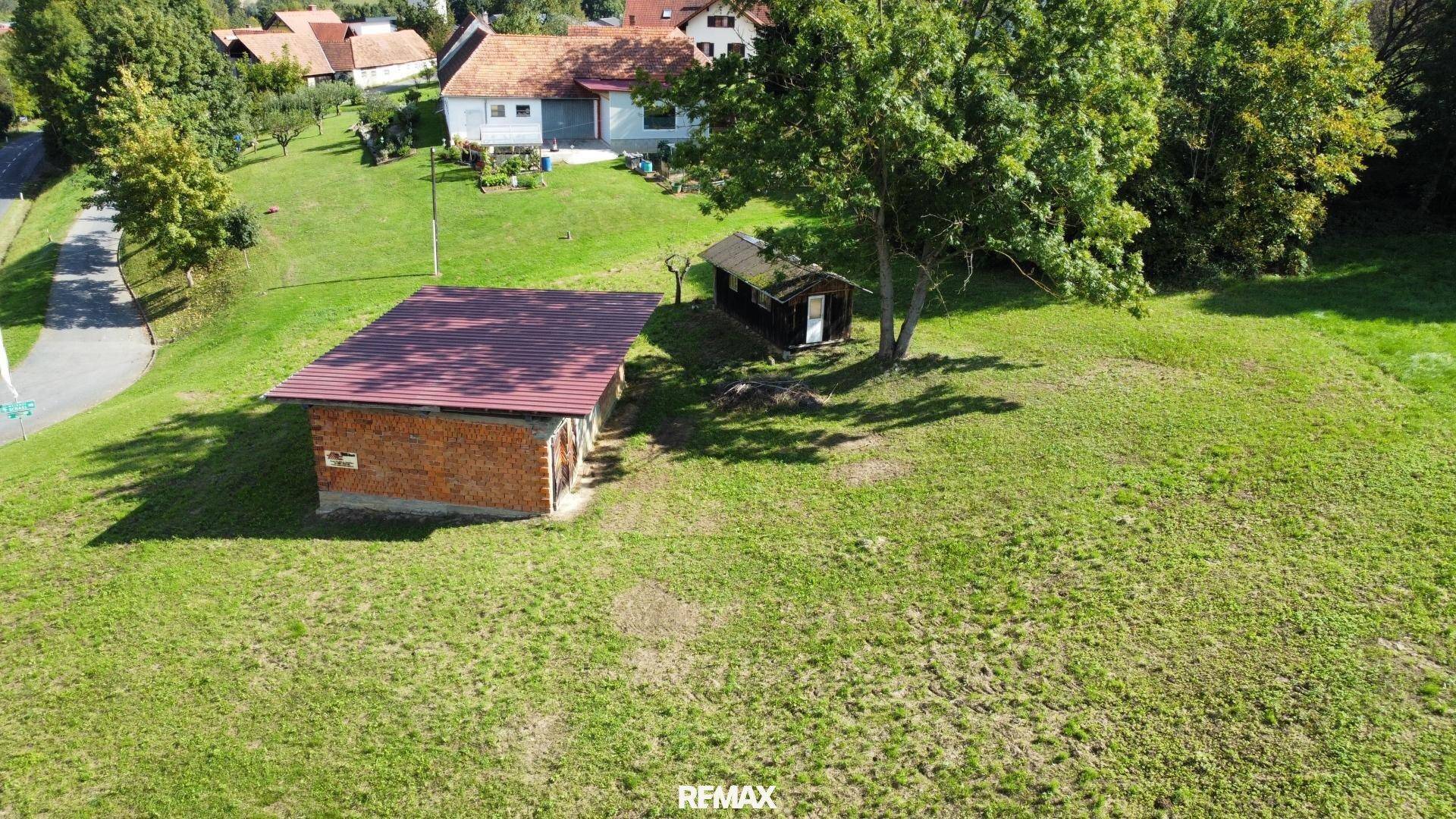 Luftaufnahme eines weitläufigen grünen Grundstücks mit einem Ziegelgebäude und einem Holzschuppen.