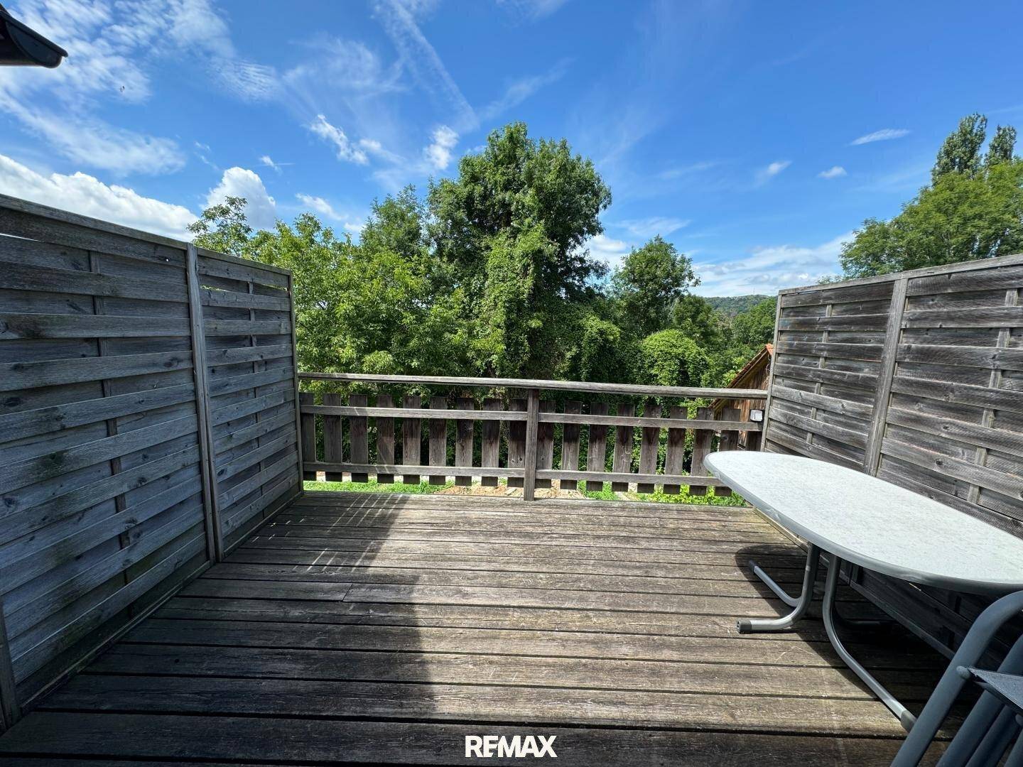 Holzterrasse mit Sitzgelegenheiten und Blick ins Grüne, umgeben von Holzzäunen.