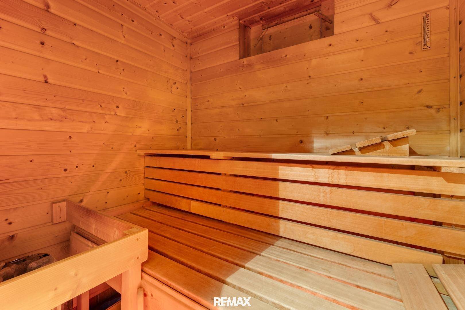 Traditionelle Holzsauna mit Bänken und Heizofen, bereit für entspannende Momente.