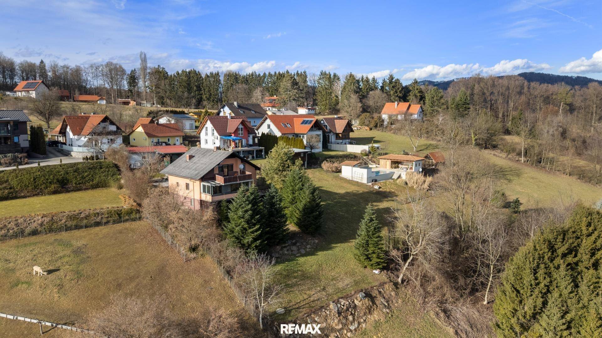 Luftaufnahme einer Wohnsiedlung eingebettet in grüne Hügel und Wälder.
