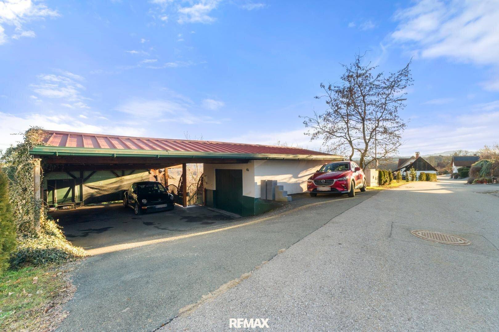 Überdachter Carport mit zwei Stellplätzen und Zufahrt auf dem Grundstück.