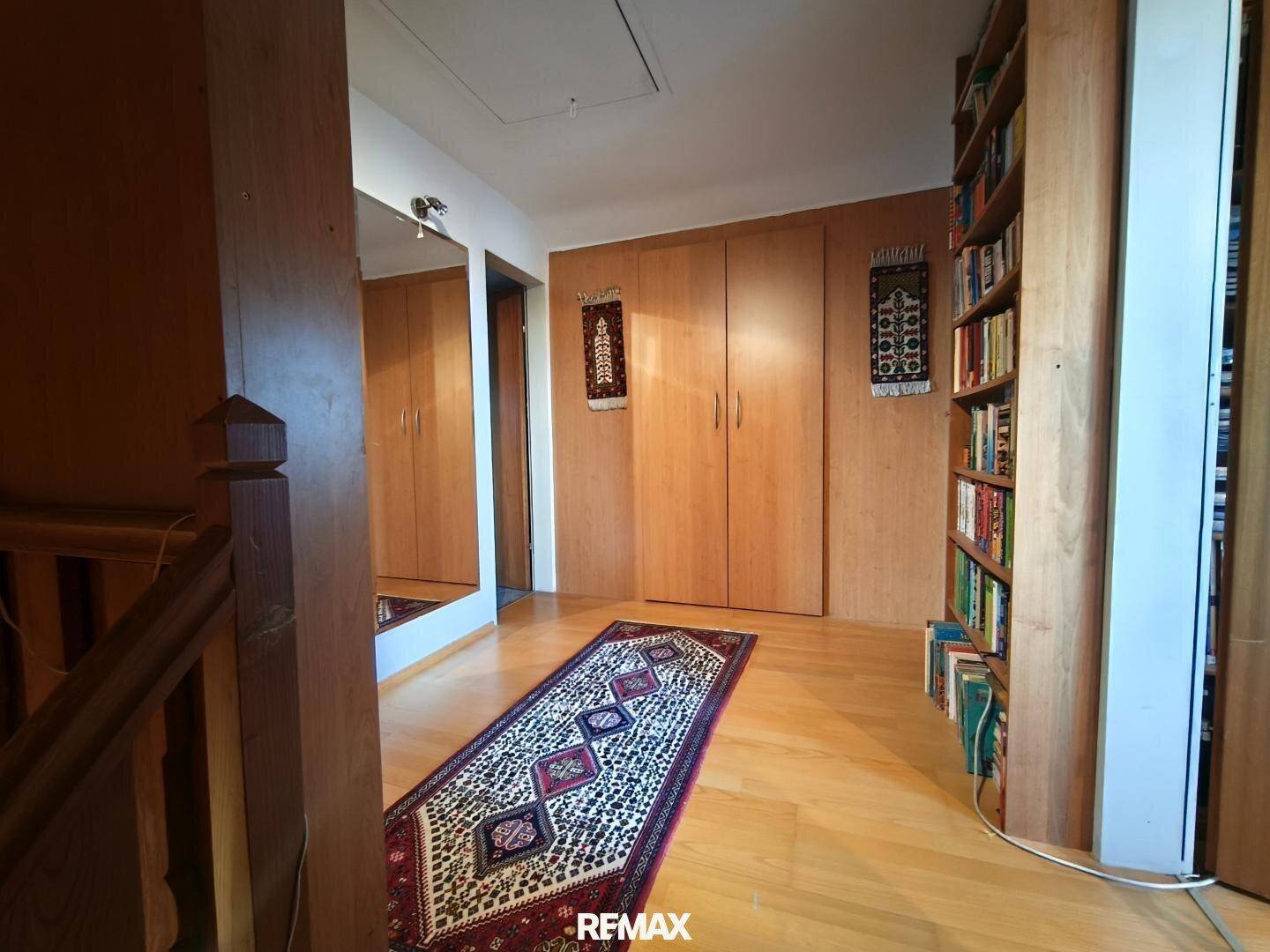 Heller Flur mit Holzboden, Einbauschränken und einem Bücherregal, das viel Stauraum bietet.