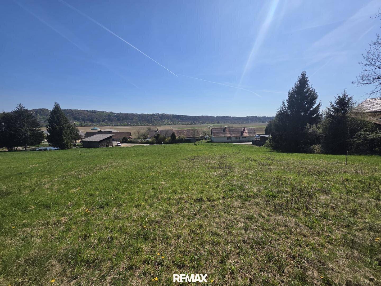 Panoramablick über ein großes grünes Grundstück mit vereinzelten Häusern und weitem Blick in die Natur.