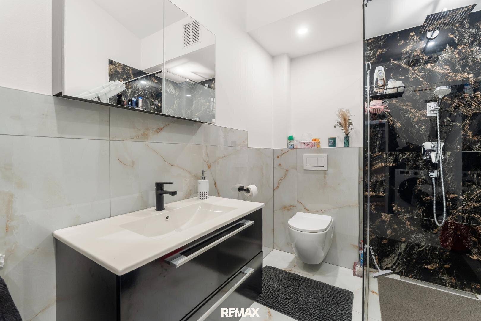 Modernes Badezimmer mit Dusche, Wand-WC und eleganten Marmorfliesen.