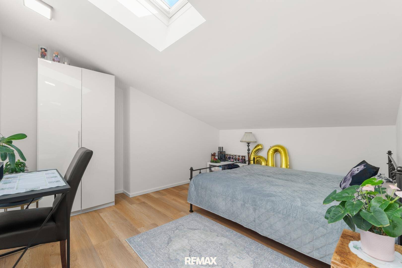 Schlafzimmer im Dachgeschoss mit Holzboden, Kleiderschrank und Dachfenster.