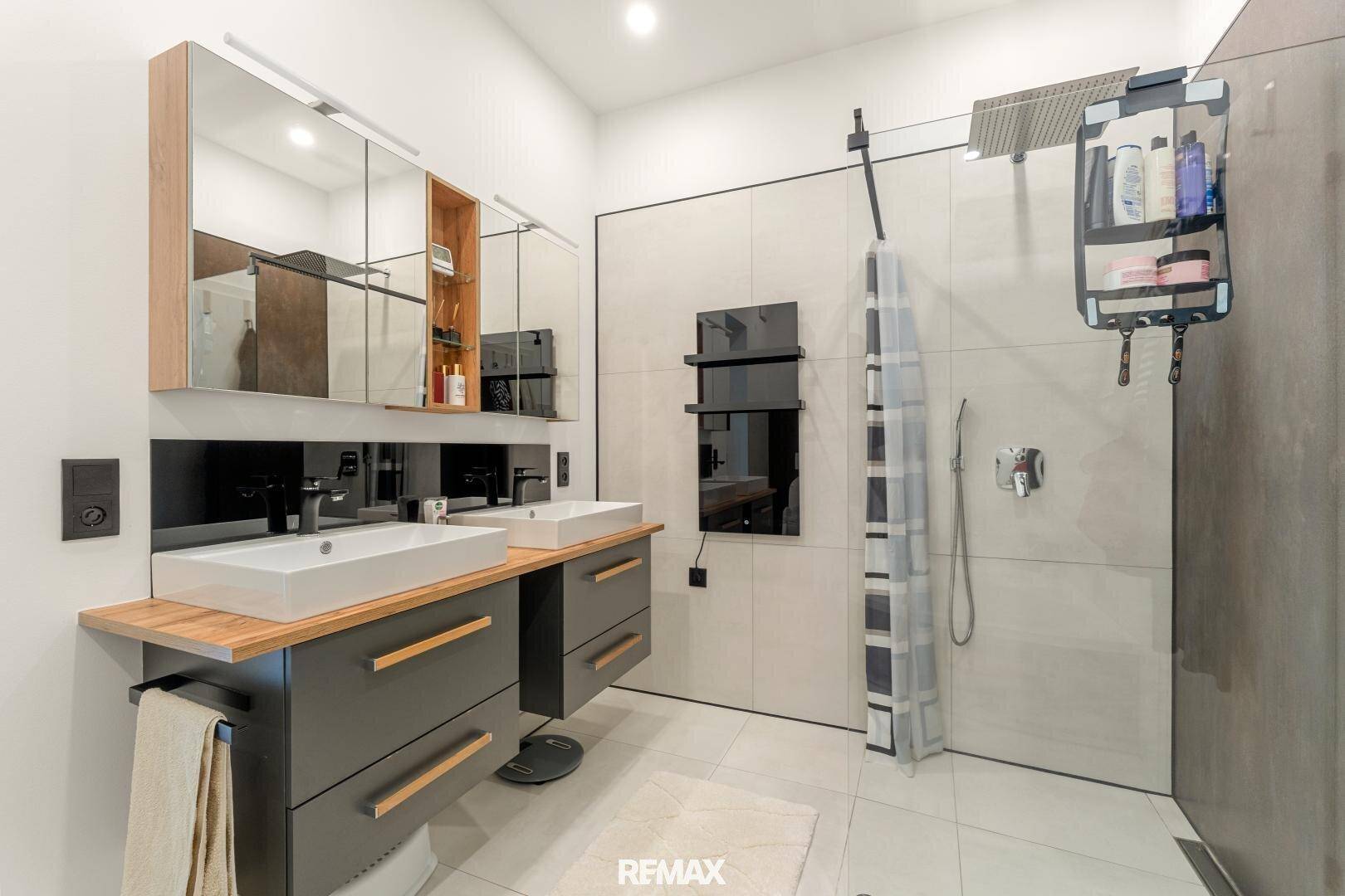 Modernes Badezimmer mit Doppelwaschbecken, großer Dusche und beheiztem Handtuchhalter.