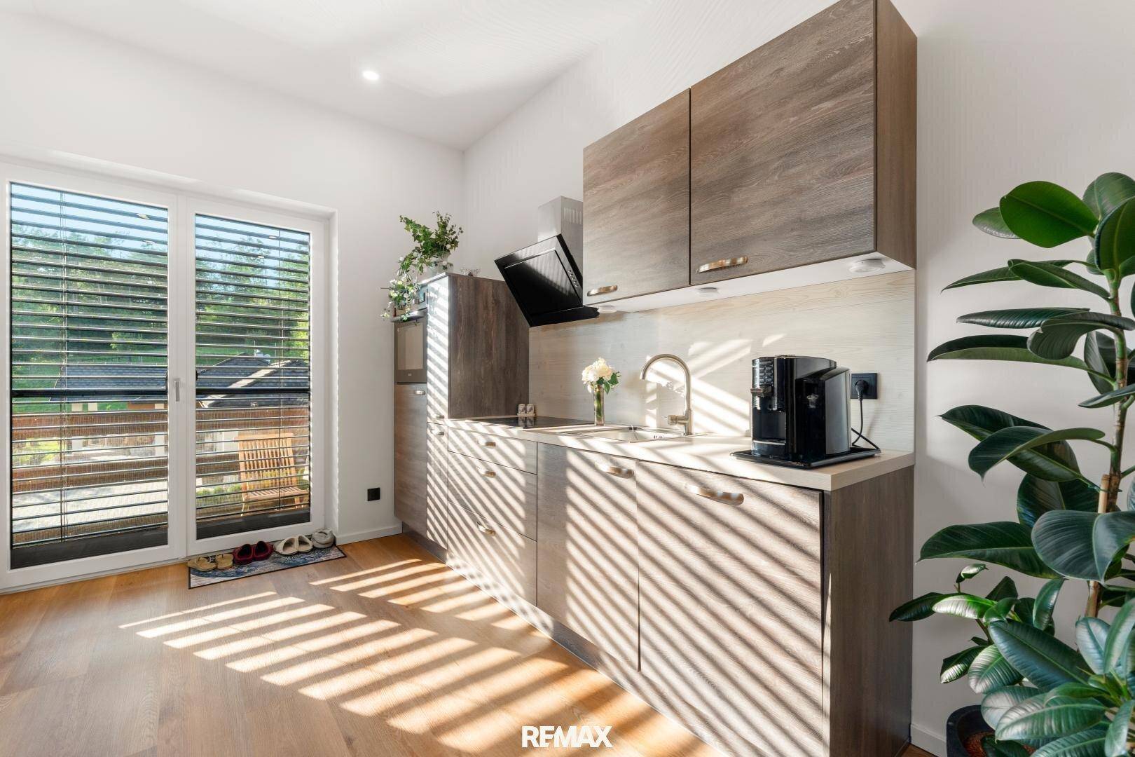 Kleine Küche mit Holzboden, modernen Schränken und Zugang zum Balkon.