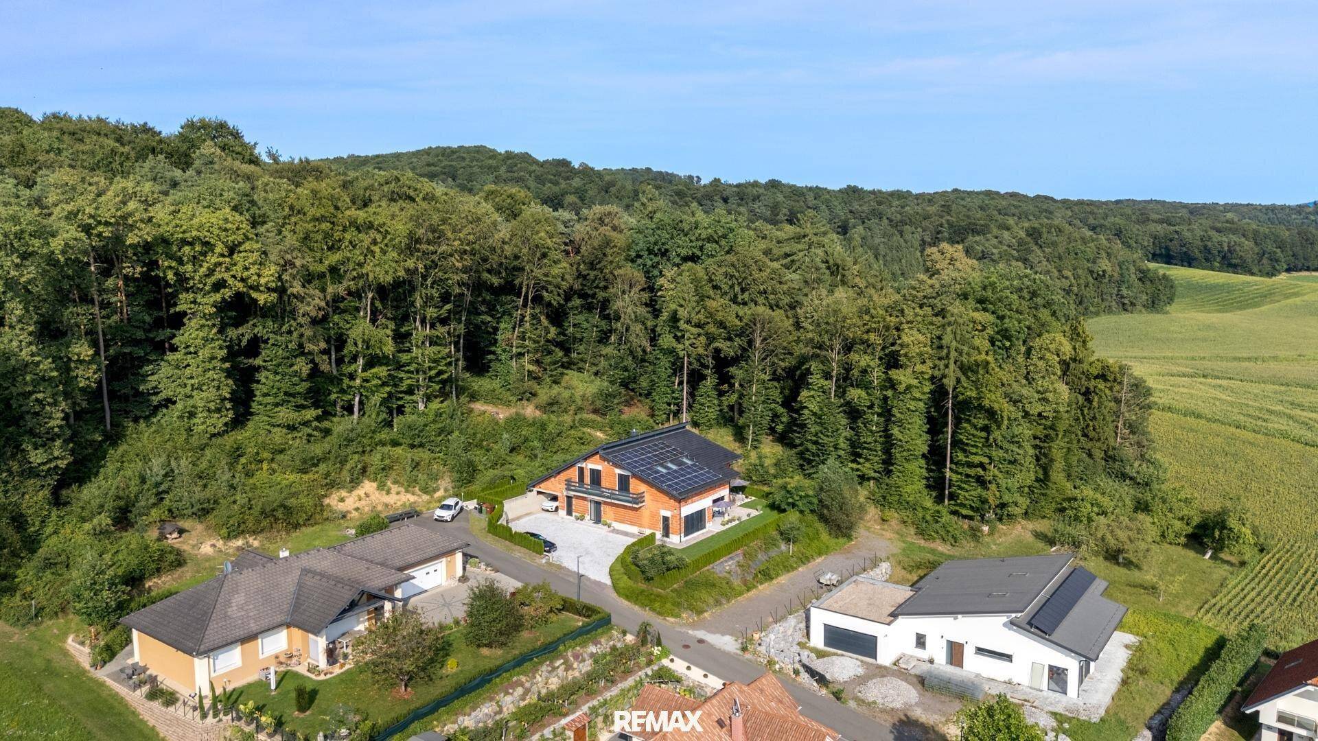 Luftaufnahme des Hauses umgeben von Wald und Feldern in einer ruhigen Wohngegend mit viel Grün.