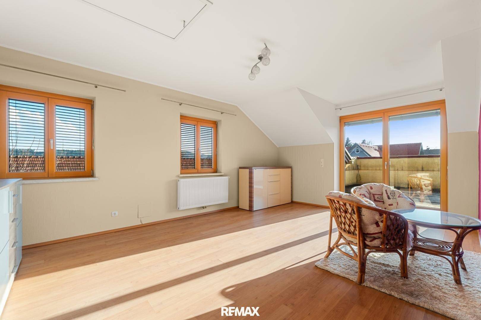 Helles Zimmer im Dachgeschoss mit Holzboden, Dachschrägen und Zugang zur Terrasse.