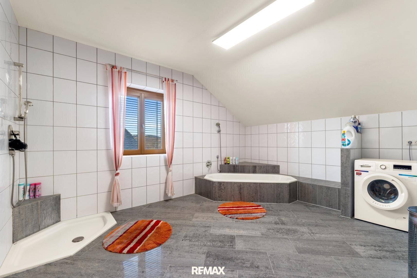 Geräumiges Badezimmer im Dachgeschoss mit Badewanne, Dusche und Waschmaschine.
