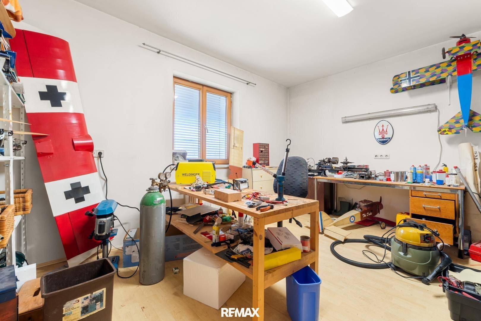 Geräumiger Hobbyraum oder Werkstatt mit Fenster, Holzboden und viel Arbeitsfläche.