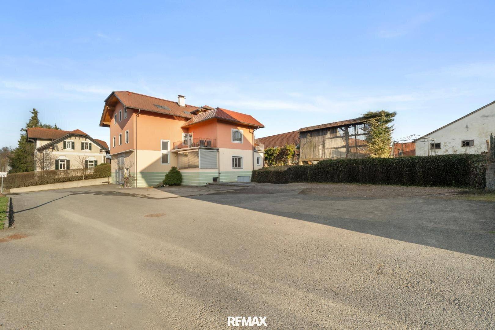 Ansicht des Hauses von der Straße mit großem Vorplatz und umliegender Hecke.