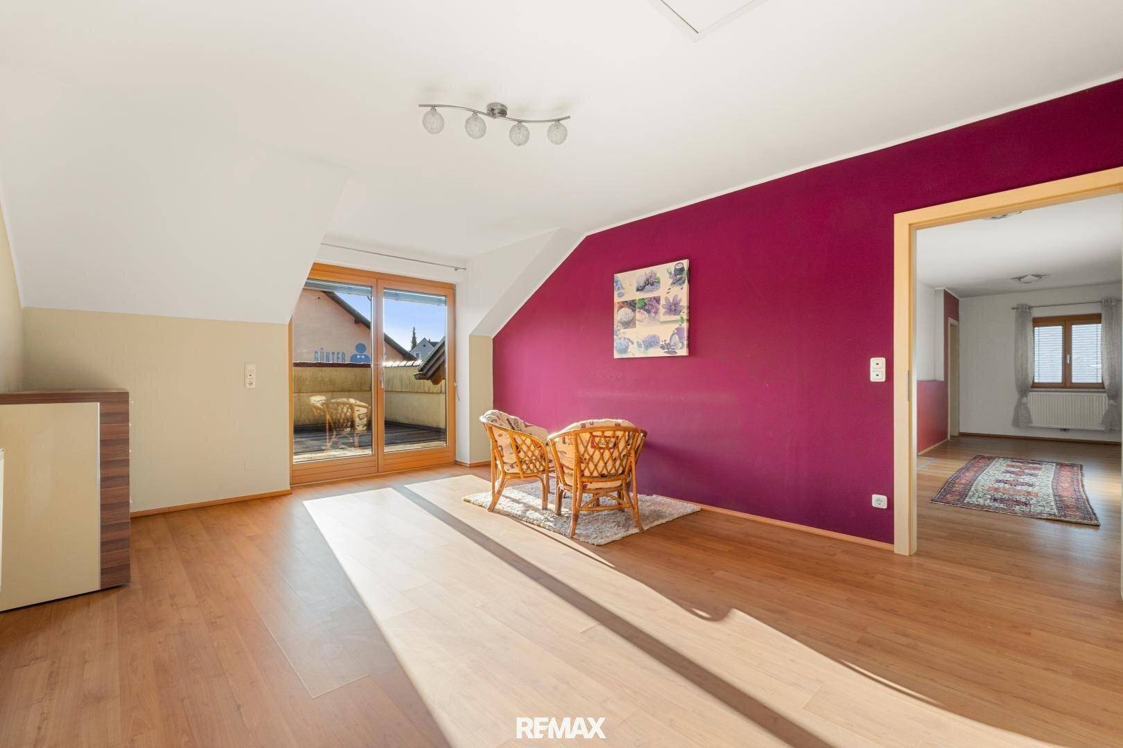 Geräumiges Zimmer mit Holzboden, farbiger Wand und Zugang zur sonnigen Dachterrasse.