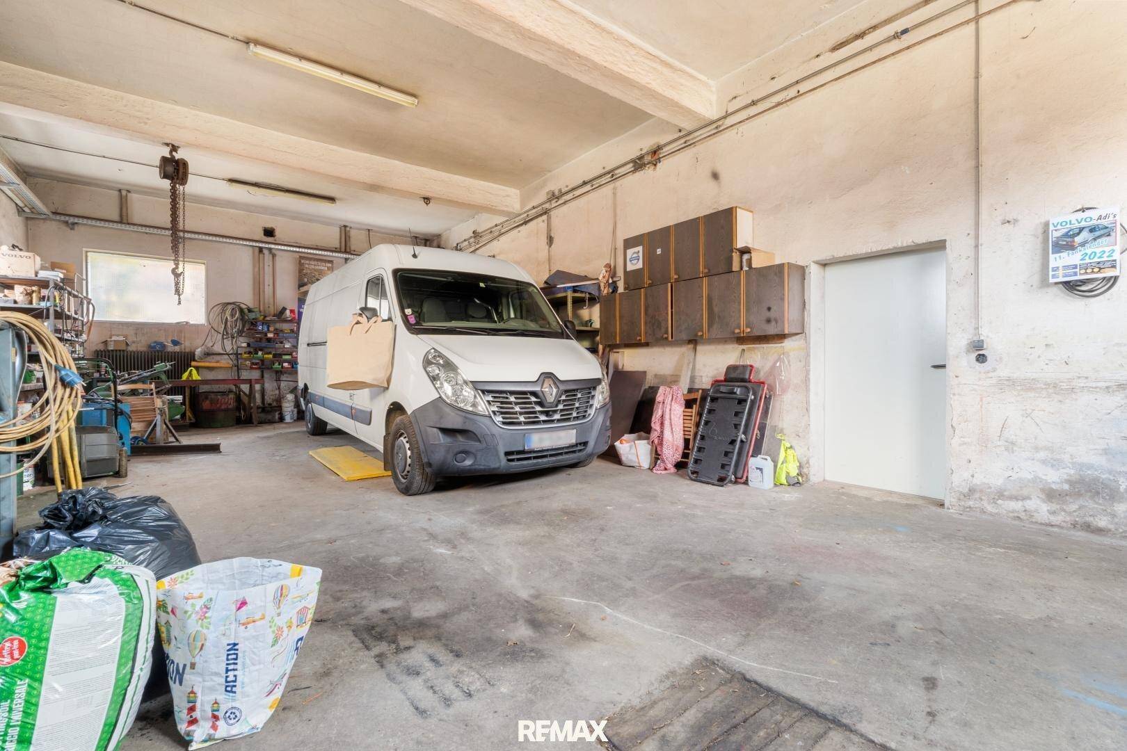 Geräumige Garage mit Betonboden, Werkzeugen und einem Lieferwagen.