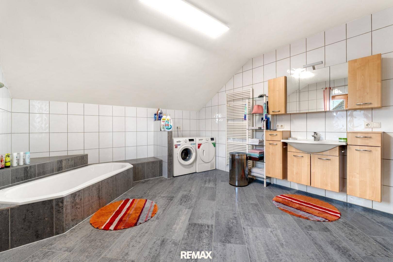 Helles Badezimmer mit Badewanne, Dusche, Waschbecken und Spiegelschrank.