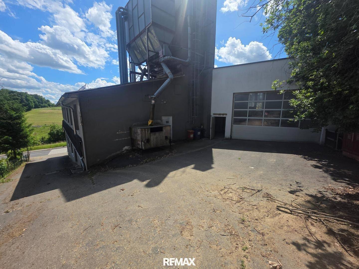 Rückseite des Gebäudes mit großem Silo und angrenzendem Feld.