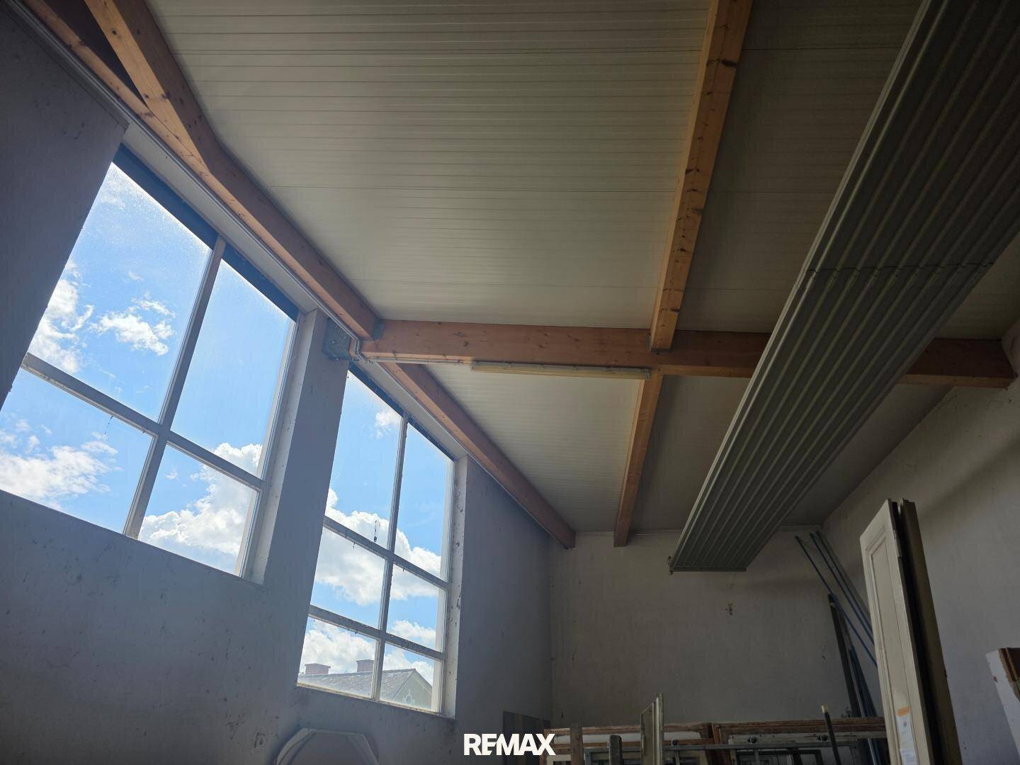 Große Fenster mit Blick auf den Himmel und eine Holzdeckenkonstruktion.