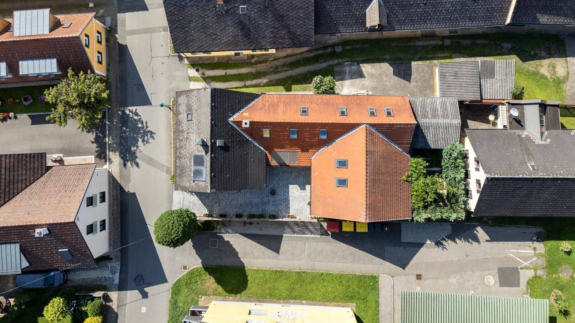 Draufsicht der Immobilie mit gepflastertem Innenhof und angrenzenden Gebäuden in der Nachbarschaft.