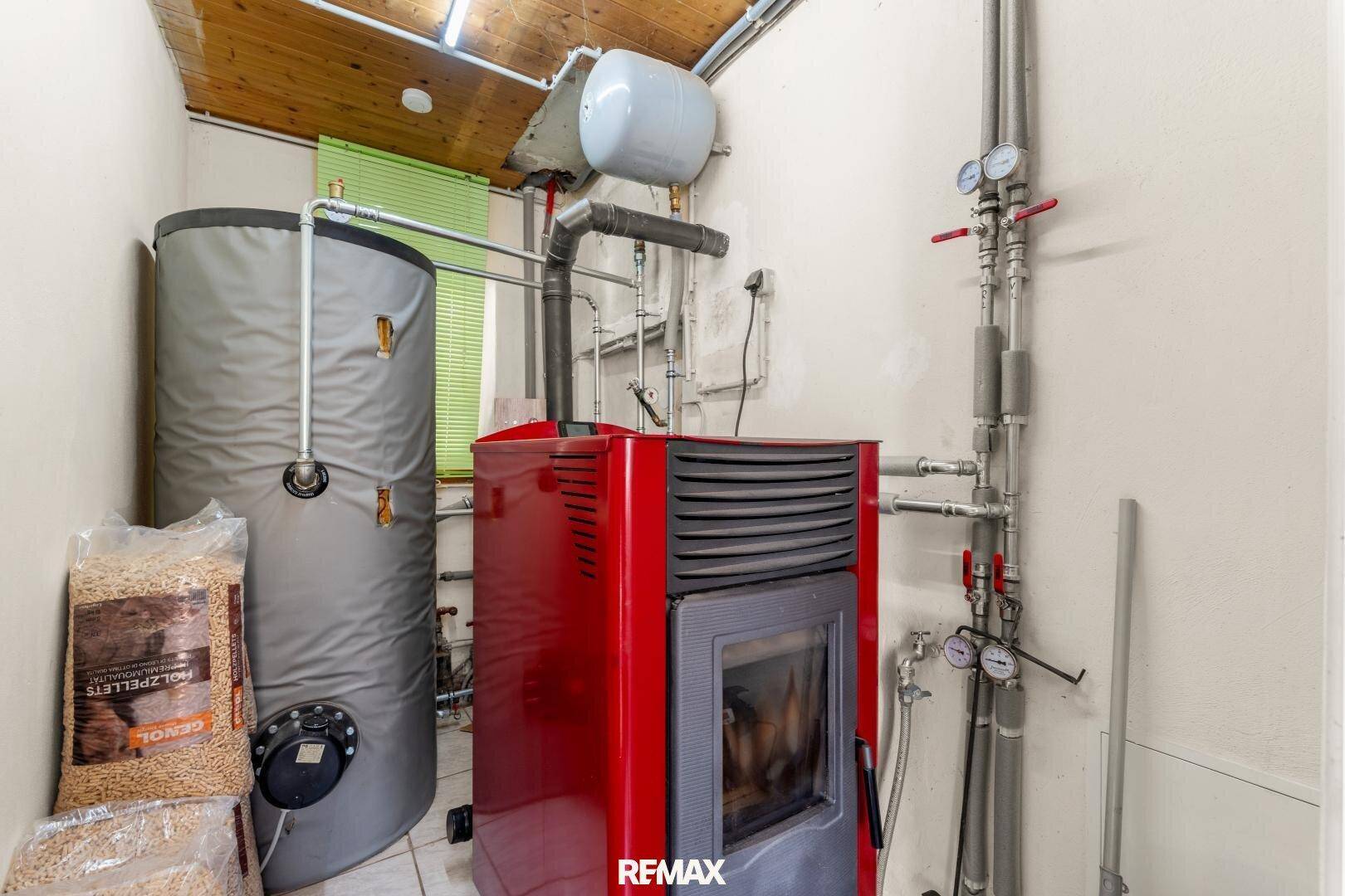 Heizungsraum mit Pelletkessel, Warmwasserspeicher und sichtbaren Rohrleitungen für die Wärmeversorgung.