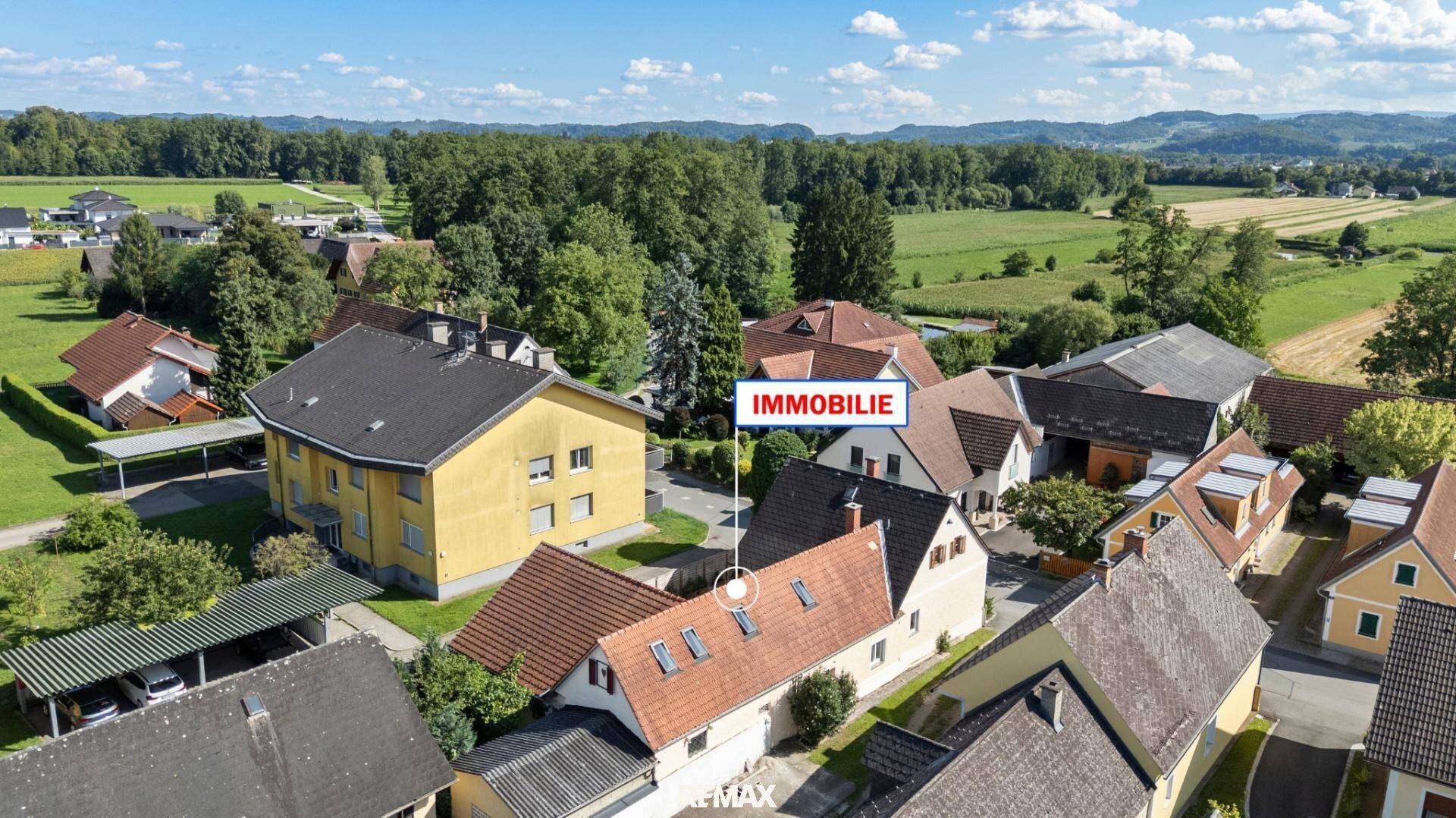 Luftaufnahme der Immobilie in ländlicher Umgebung mit Feldern und Wäldern unter blauem Himmel.