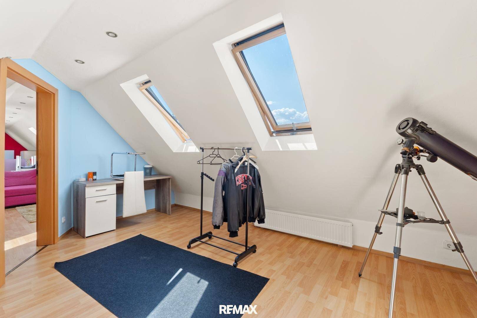 Arbeitsbereich im Dachgeschoss mit Schreibtisch, Stuhl und Dachfenstern für eine angenehme Atmosphäre.