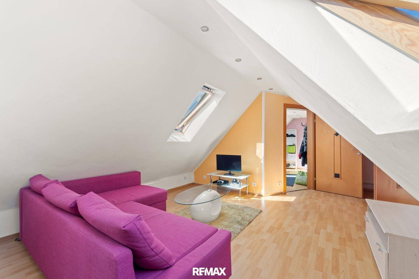 Helles Wohnzimmer im Dachgeschoss mit Dachschrägen und Dachfenstern für viel Licht.