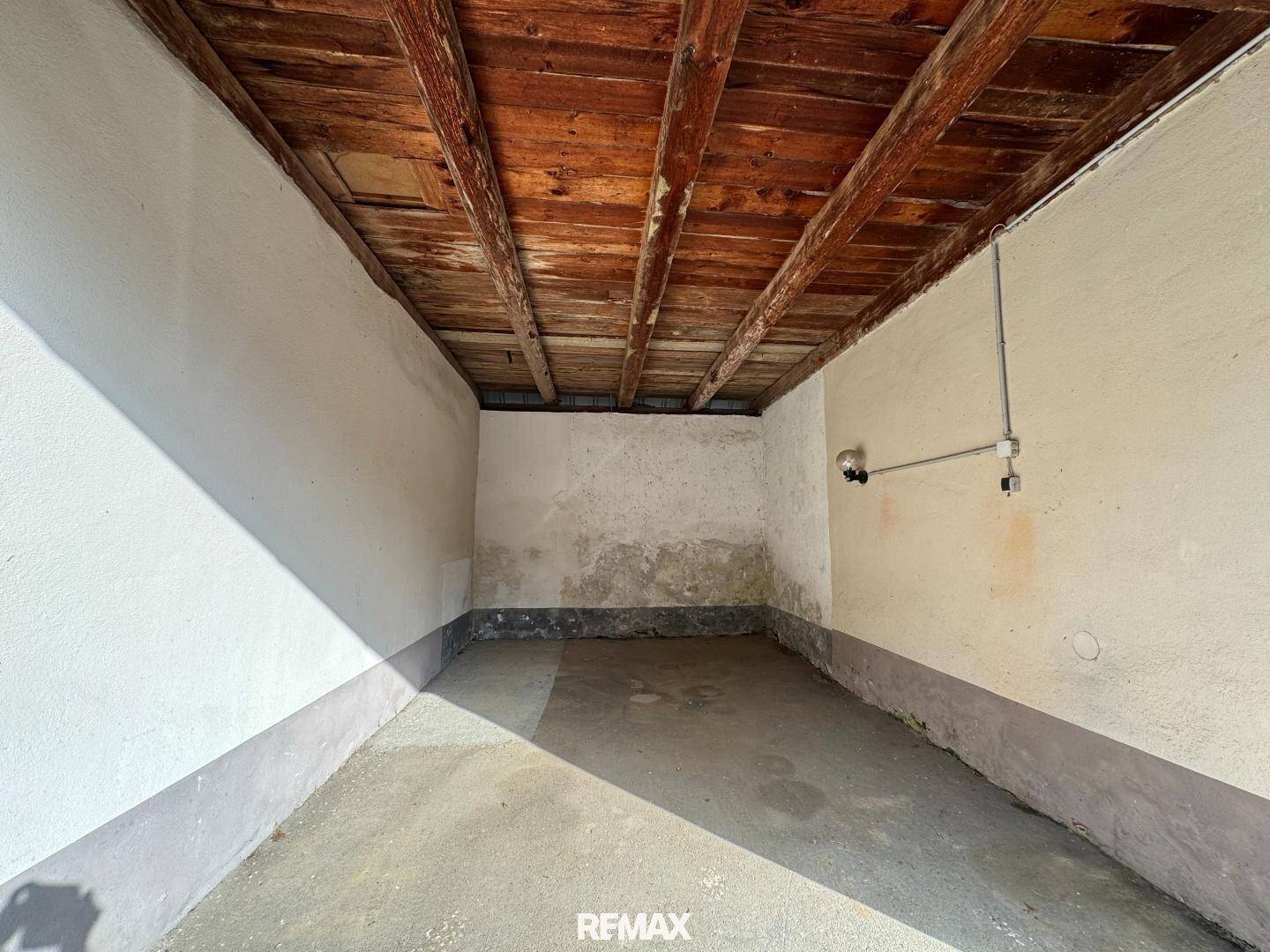 Leerer Raum mit Holzbalkendecke und Betonboden, geeignet als Werkstatt oder Lagerfläche.