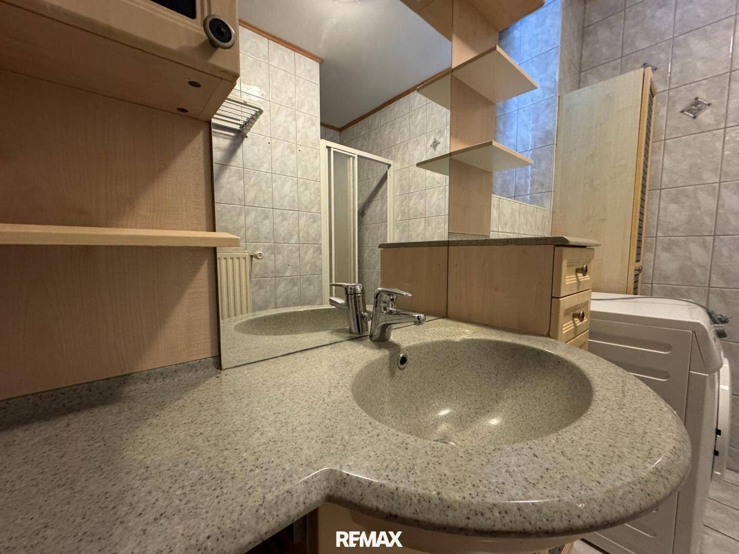 Nahaufnahme des Waschbeckens mit Granit-Arbeitsplatte und Spiegelschrank im Badezimmer.
