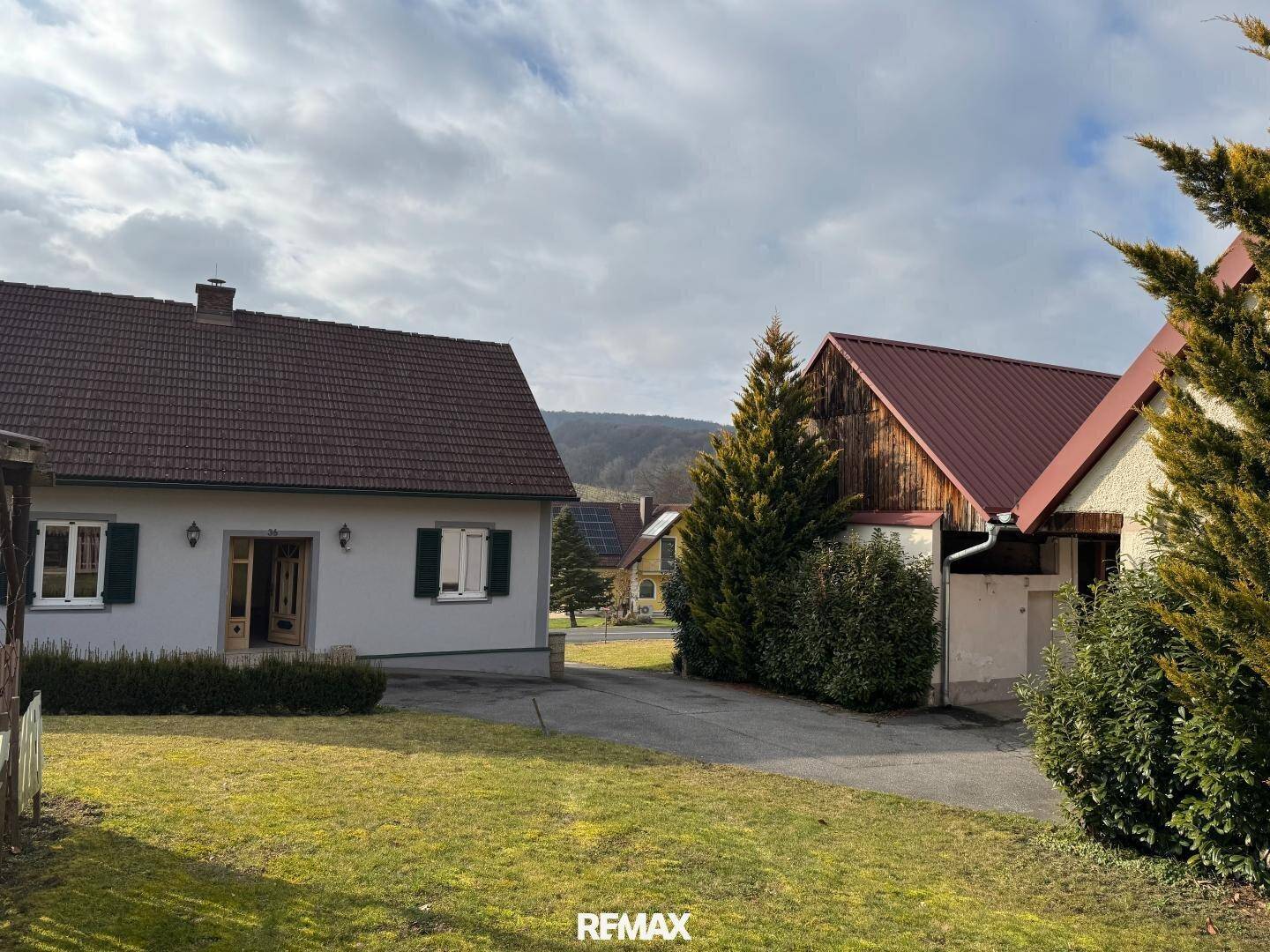 Einfamilienhaus mit rotem Ziegeldach und gepflegtem Vorgarten in ländlicher Umgebung.