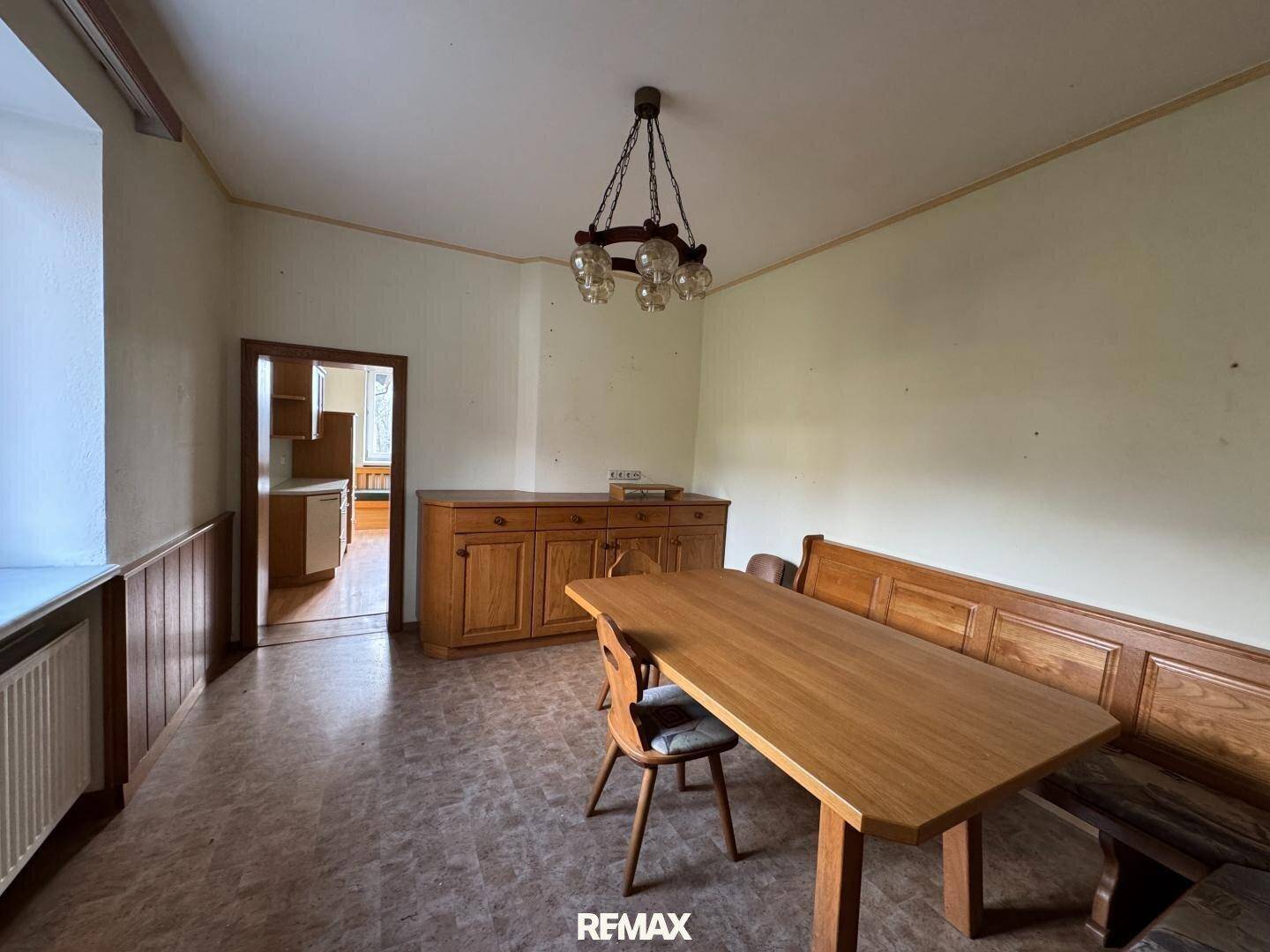 Traditioneller Essbereich mit Holztisch, Eckbank und Blick in einen angrenzenden Raum.