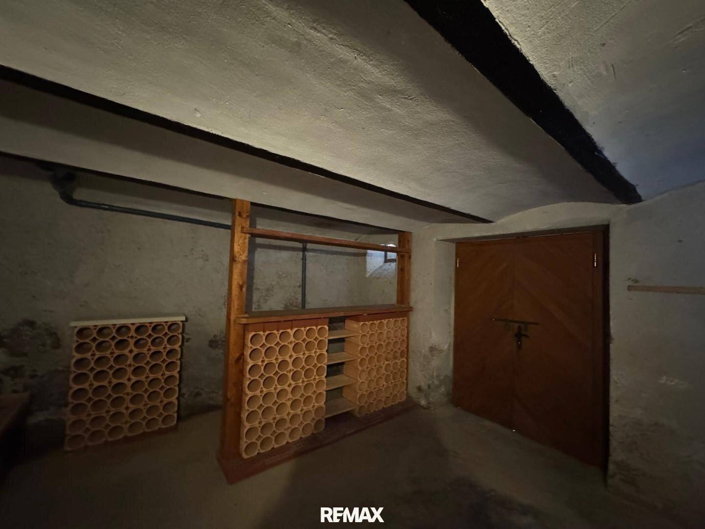 Traditioneller Weinkeller mit Regalen aus Terrakotta und Holztür, ideal zur Weinlagerung.