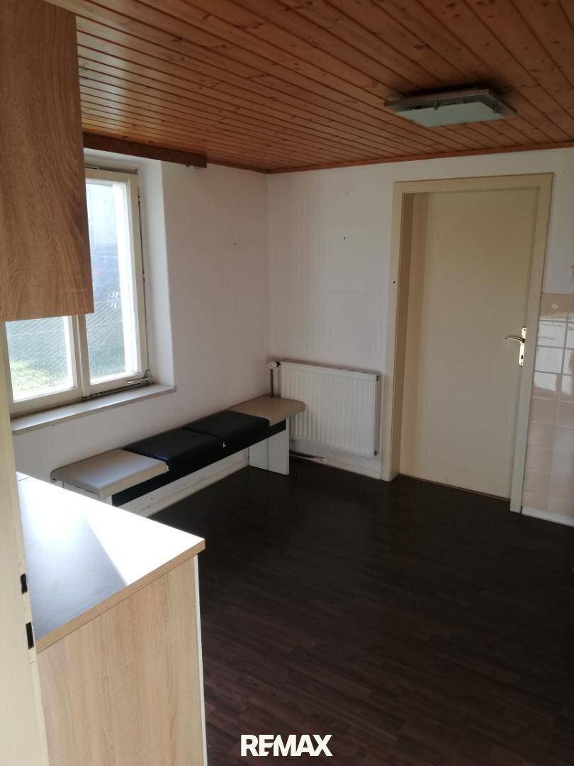 Küchenbereich mit Holzdeckenverkleidung, Fenster und einer integrierten Sitzbank, ideal für eine kleine Essecke.
