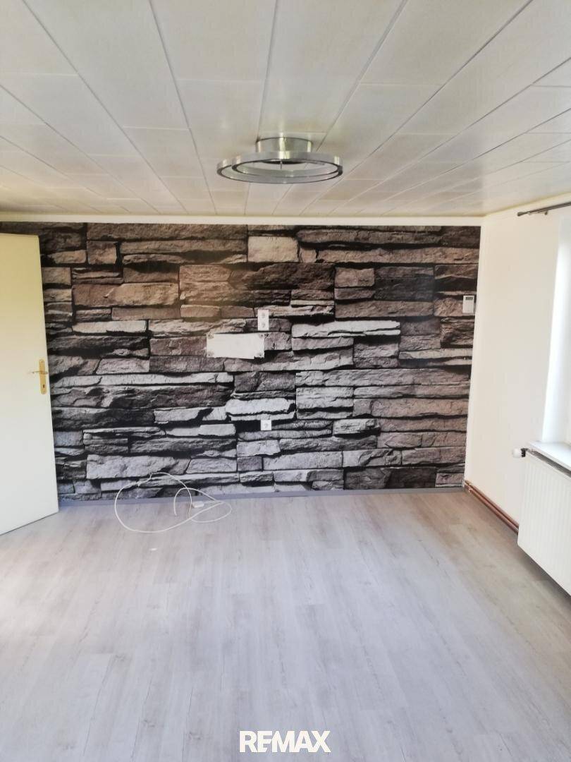 Zimmer mit Laminatboden und einer Akzentwand in Steinoptik, bereit für individuelle Gestaltung.