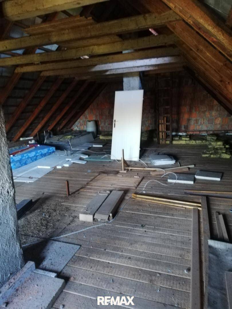 Unausgebauter Dachboden mit sichtbaren Holzbalken und Dielenboden, bietet Ausbaupotenzial.
