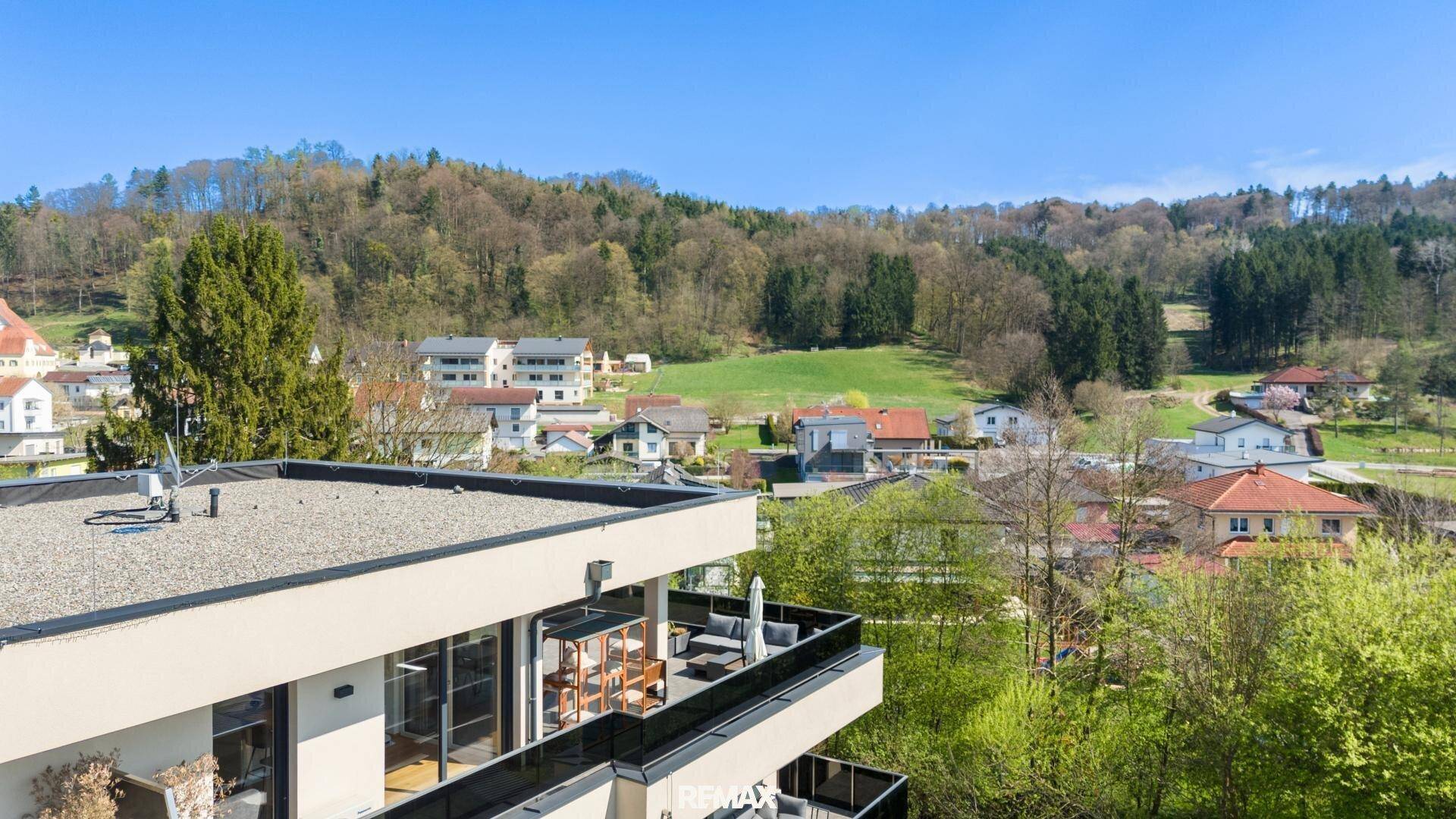 Gebäudeansicht mit Dachterrasse und weitem Blick über die grüne Hügellandschaft.