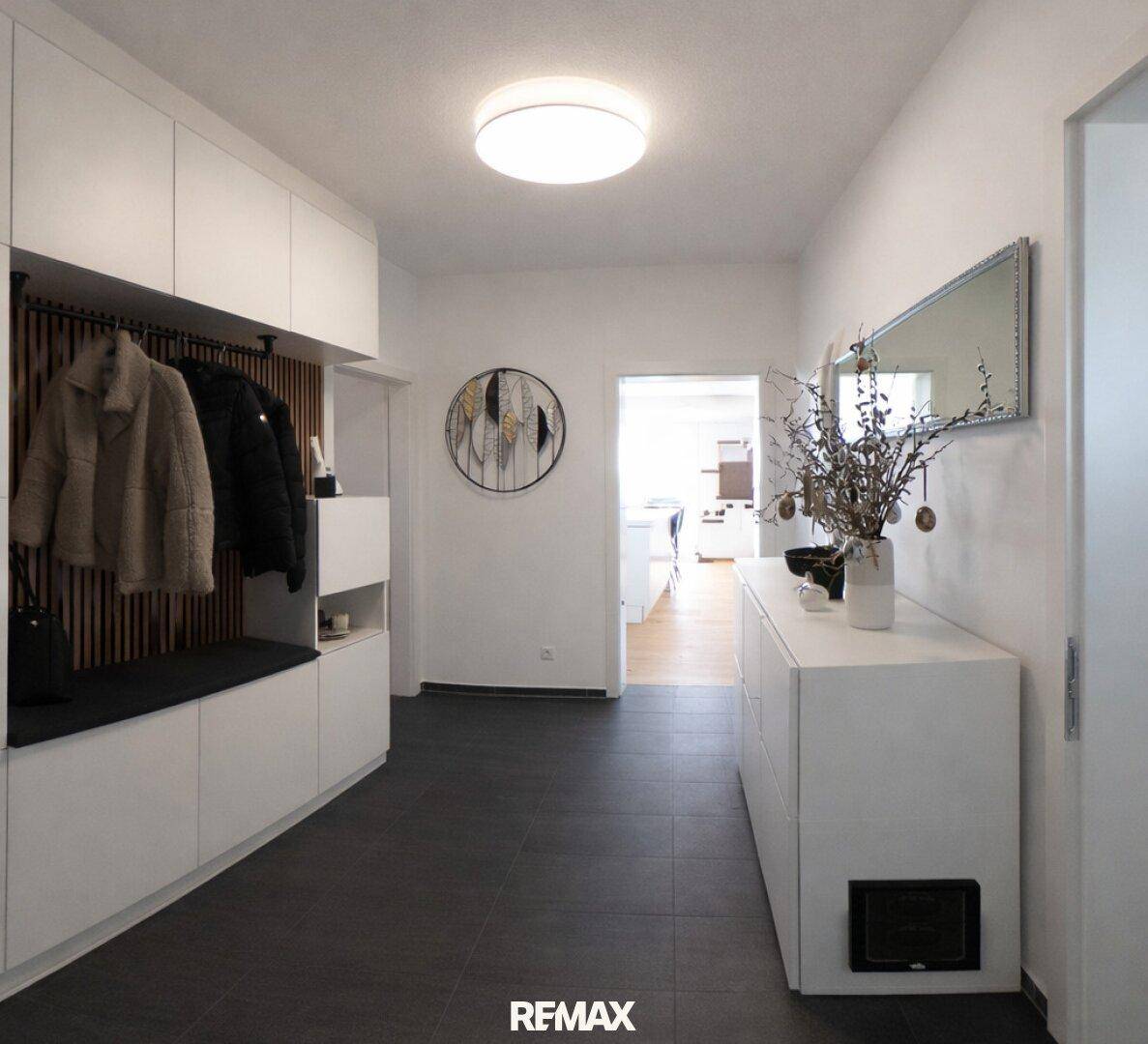Heller Eingangsbereich mit moderner Garderobe und dunklen Fliesenboden.