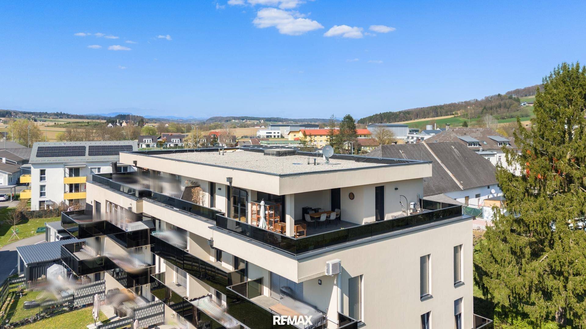 Modernes Mehrfamilienhaus mit Flachdach und großzügigen Balkonen in ländlicher Umgebung.