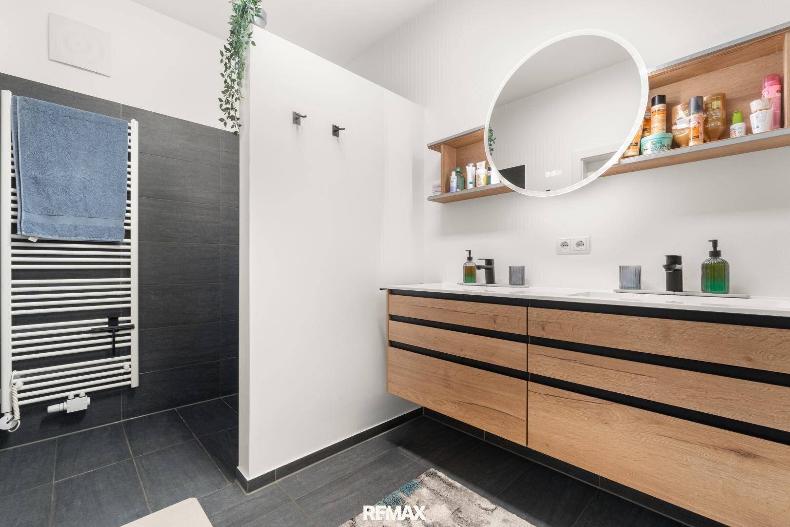 Modernes Badezimmer mit Doppelwaschbecken, begehbarer Dusche und Handtuchheizkörper.