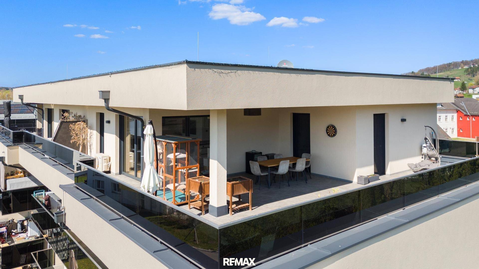 Ansicht des modernen Gebäudes mit großer Dachterrasse und umliegender Landschaft.